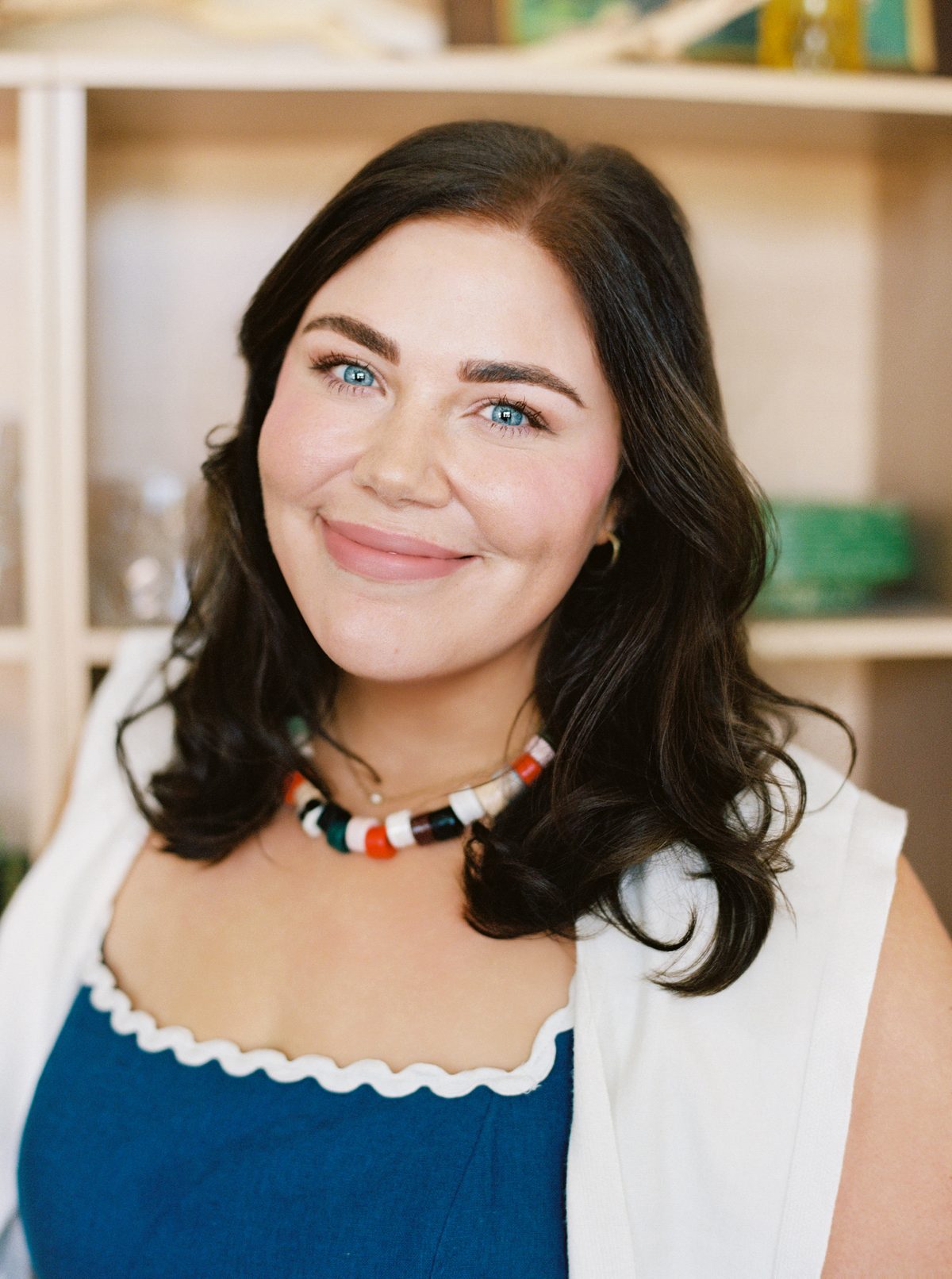 Close-up portrait of Paige Vaughn smiling, with a light-wood shelf behind her